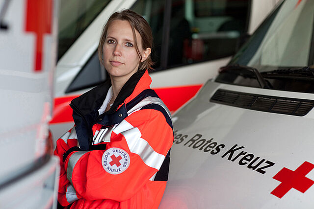 DRK Notfallsanitäterin vor Einsatzfahrzeug