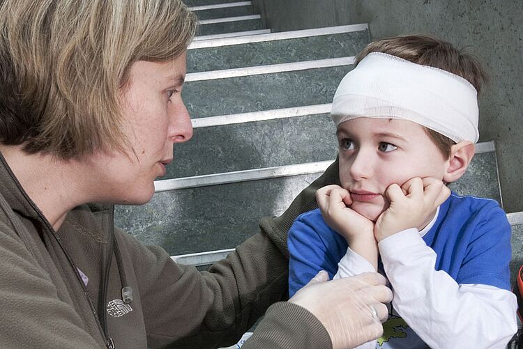 DRK Emsland Erste Hilfe Unfälle mit Kindern Ein Frau sitzt bei einem Kind mit Kopfverband