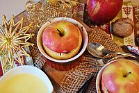 ein lecker zubereiteter Bratapfel liegt auf einem weihnachtlich gedeckten Tisch